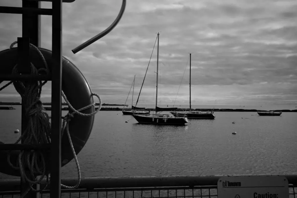 Sailboats float on the water under cloudy skies