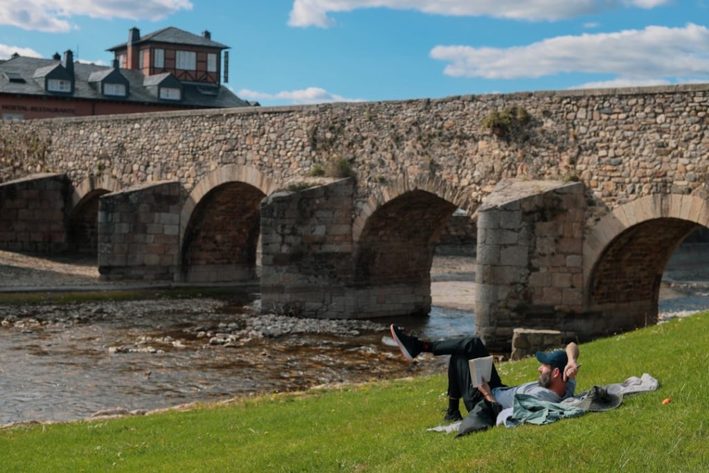 a man and woman sitting on the grass next to a river – Foto de Mor Shani en Unsplash
