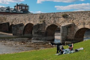 a man and woman sitting on the grass next to a river – Foto de Mor Shani en Unsplash