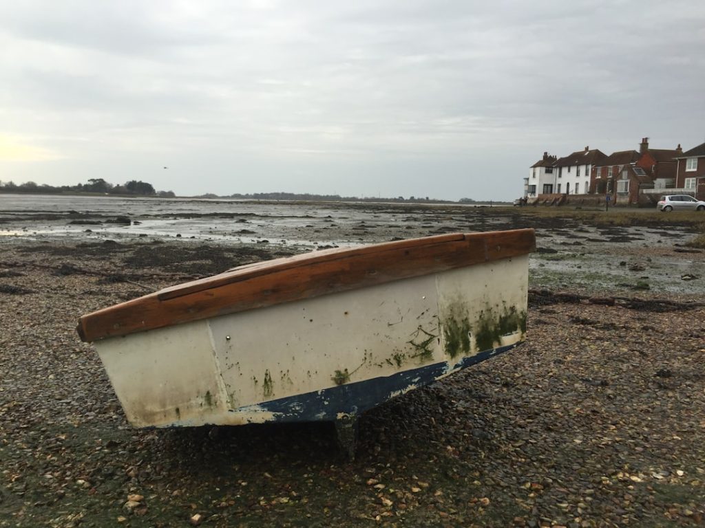 A small rowboat rests on a pebble beach. – Foto de Tanya Barrow en Unsplash