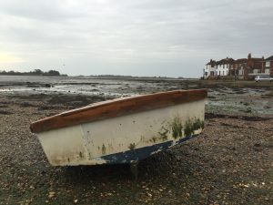 A small rowboat rests on a pebble beach. – Foto de Tanya Barrow en Unsplash